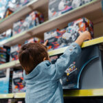 Little boy at the shelf in kids store, side view