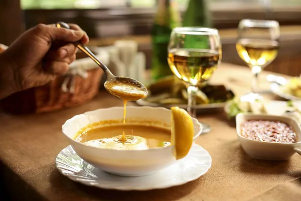 side view of lentil merci soup in a bowl and a hand with a spoon over the bowl