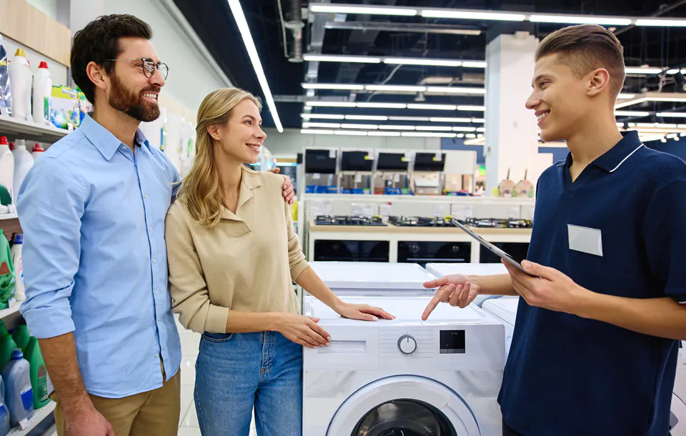A couple actively engaging and negotiating with a salesperson in an electronics store